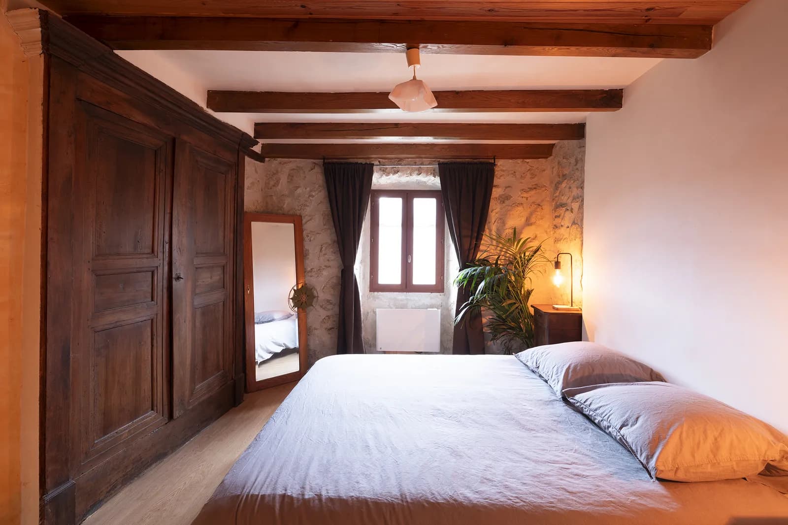 Chambre de la Maison des Châtaigniers avec armoire ancienne et murs en pierre